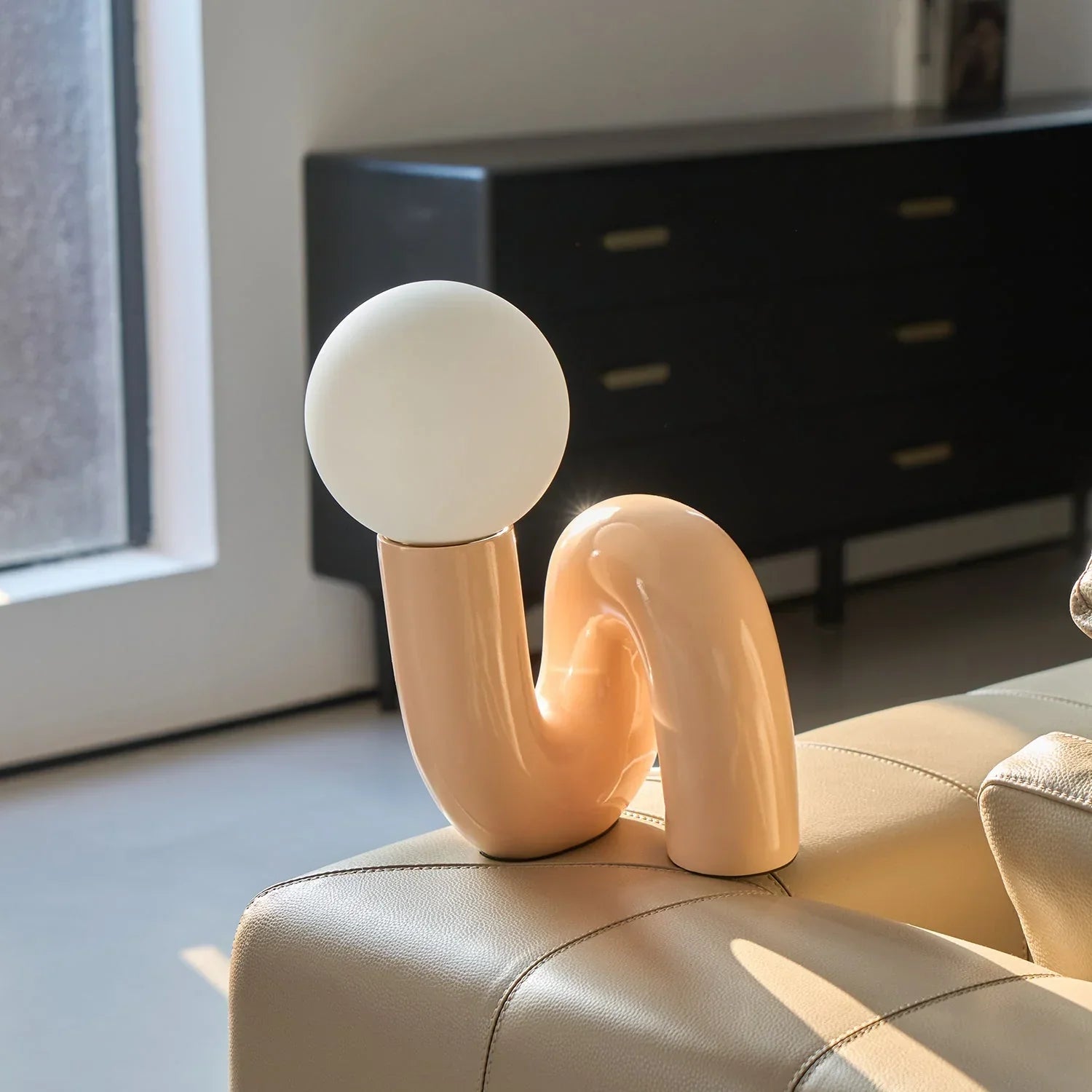 Groovy peach table lamp with curved design on beige leather sofa, modern home decor