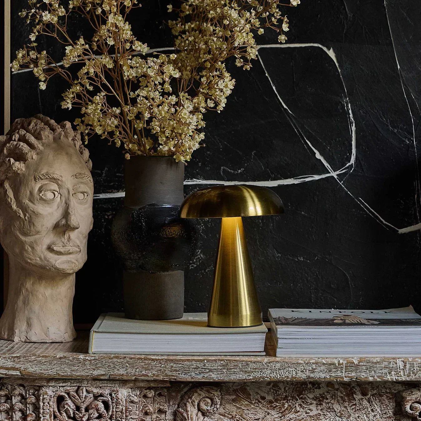 Golden mushroom lamp on rustic shelf with dried flowers and sculpted head decor
