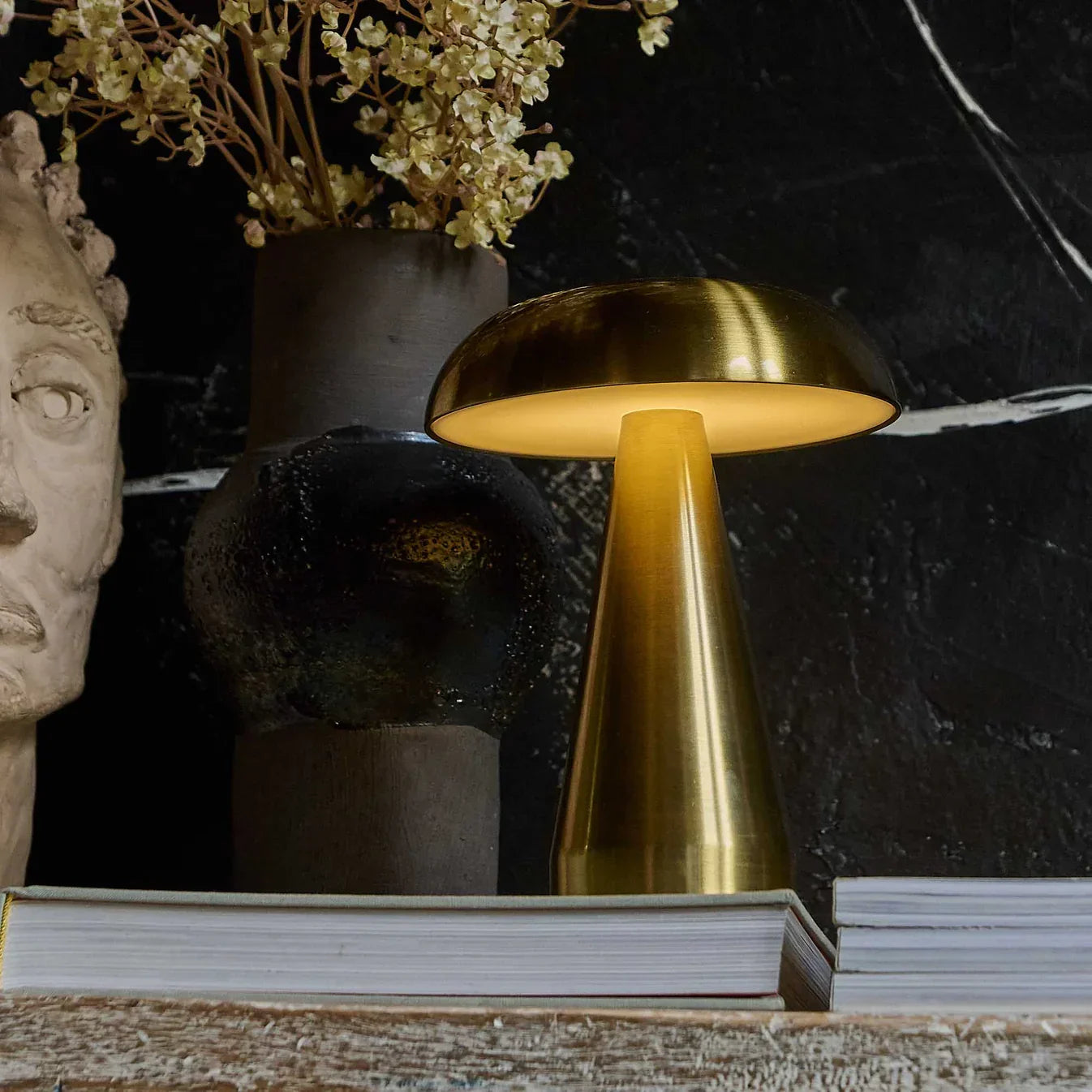 Golden mushroom-style table lamp glowing warmly on rustic shelf with decor