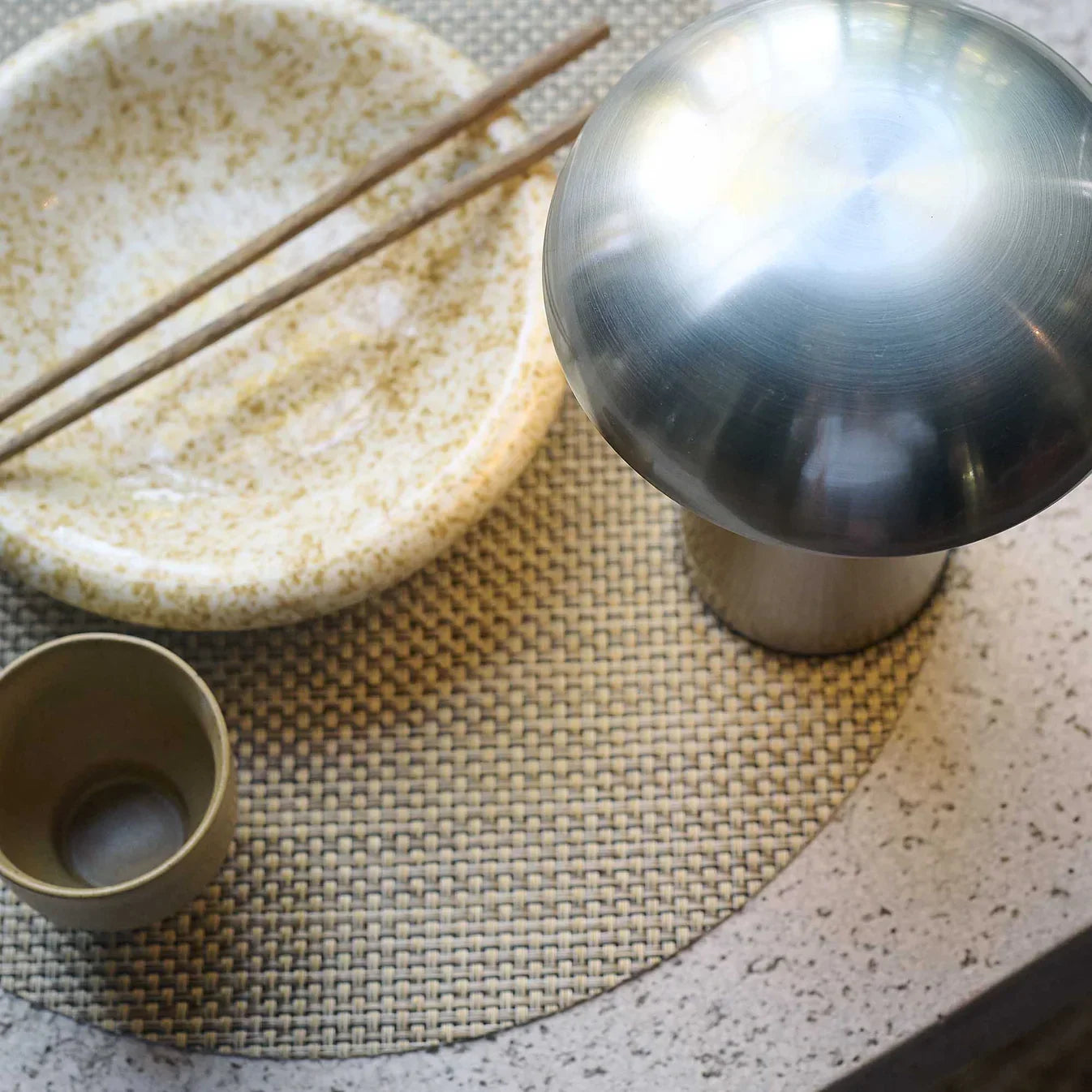 Stylish metallic table lamp with woven mat and ceramic dish, perfect for modern home decor