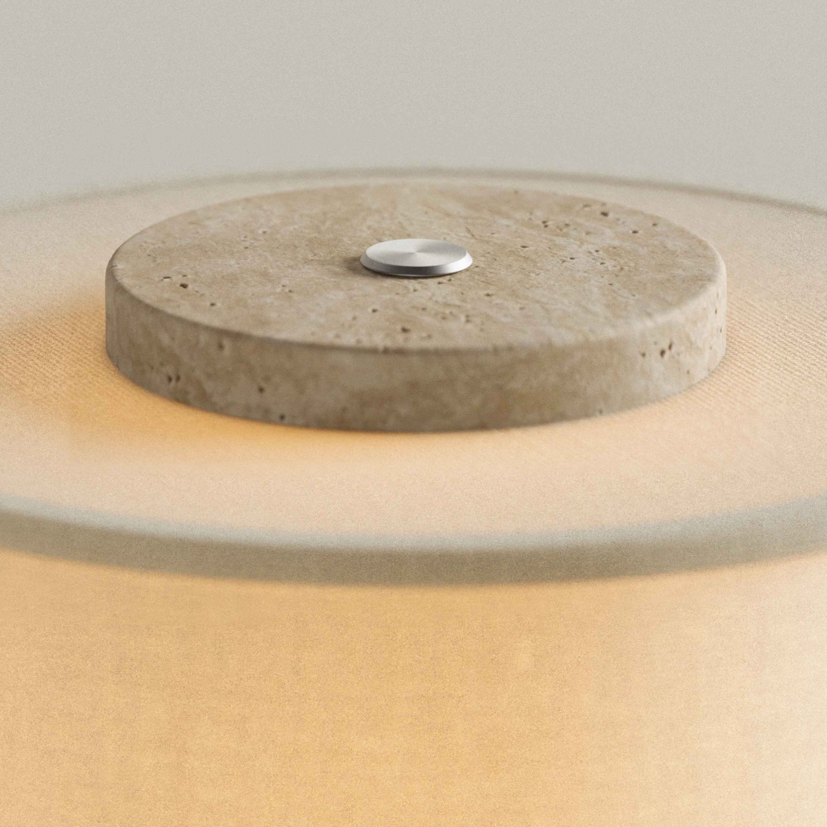 Travertine stone cap with touch button on top of the Olbia Portable Lamp's glowing drum shade