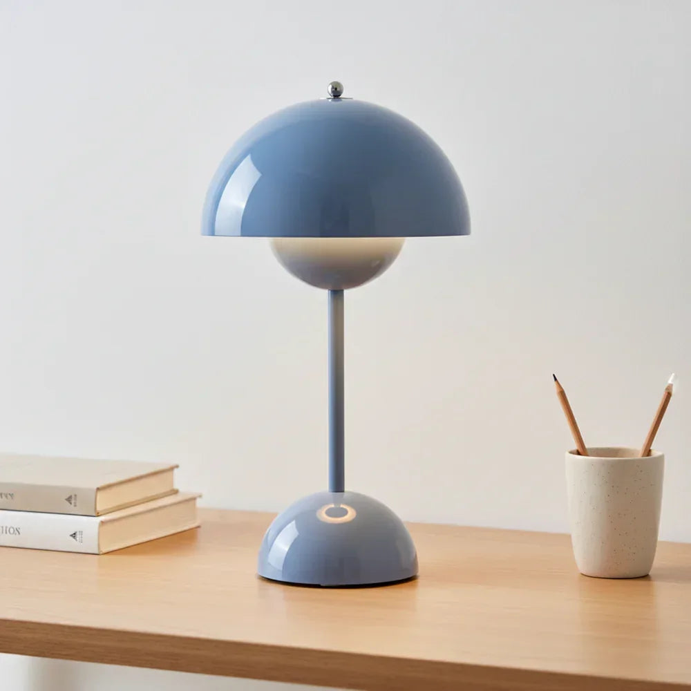Modern blue dome table lamp on wooden desk with books and pencils, stylish home decor lighting