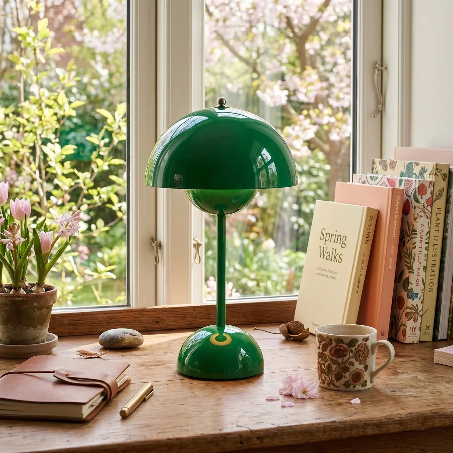 Groovy green dome table lamp on wooden desk with books, flowers, and spring window view