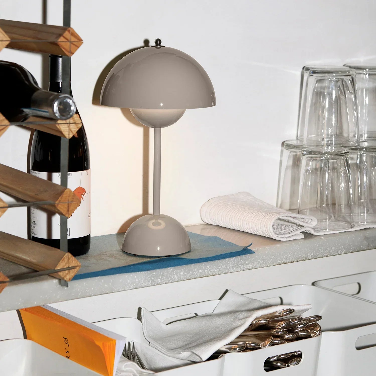 Grey dome table lamp on kitchen counter with wine bottle and glassware, modern funky lighting