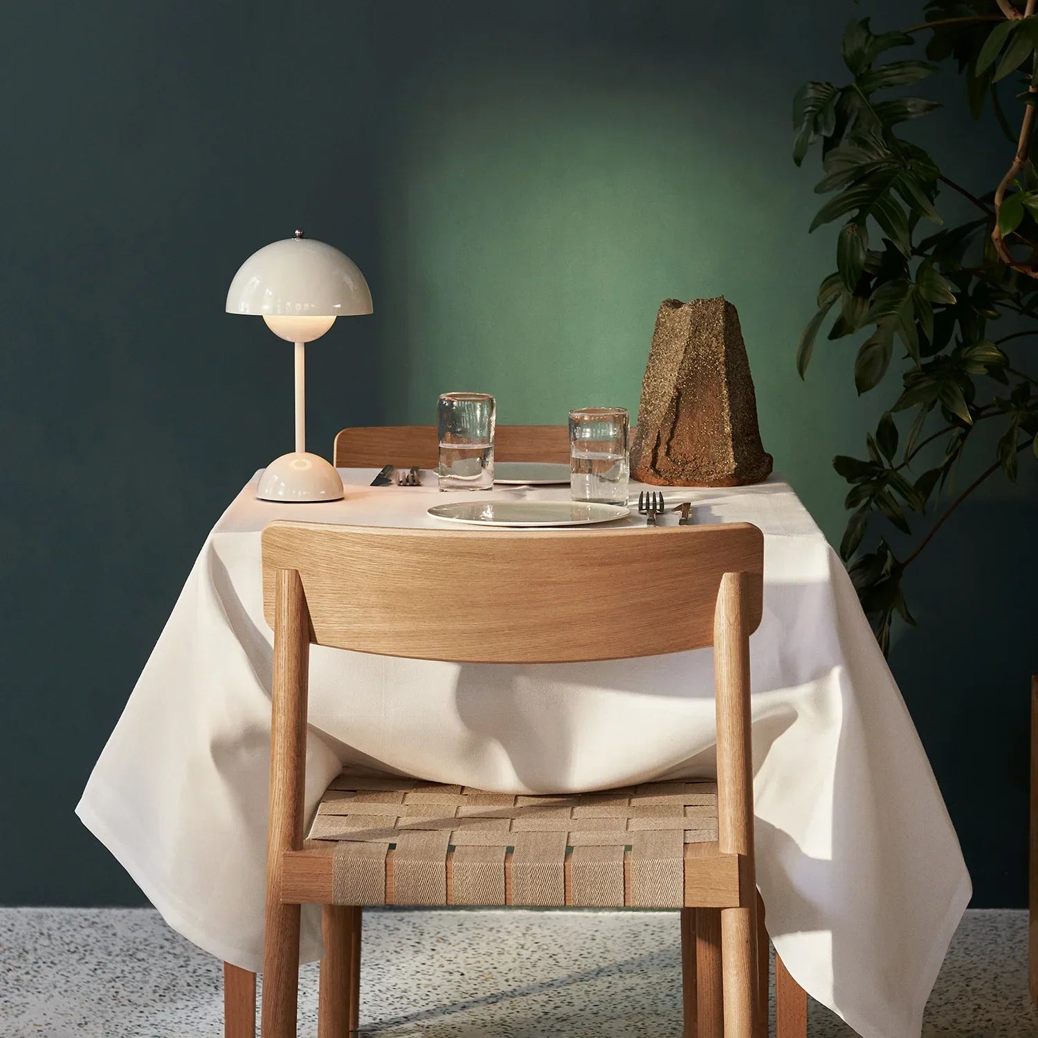 Modern white dome table lamp on dining table with wooden chair and green wall